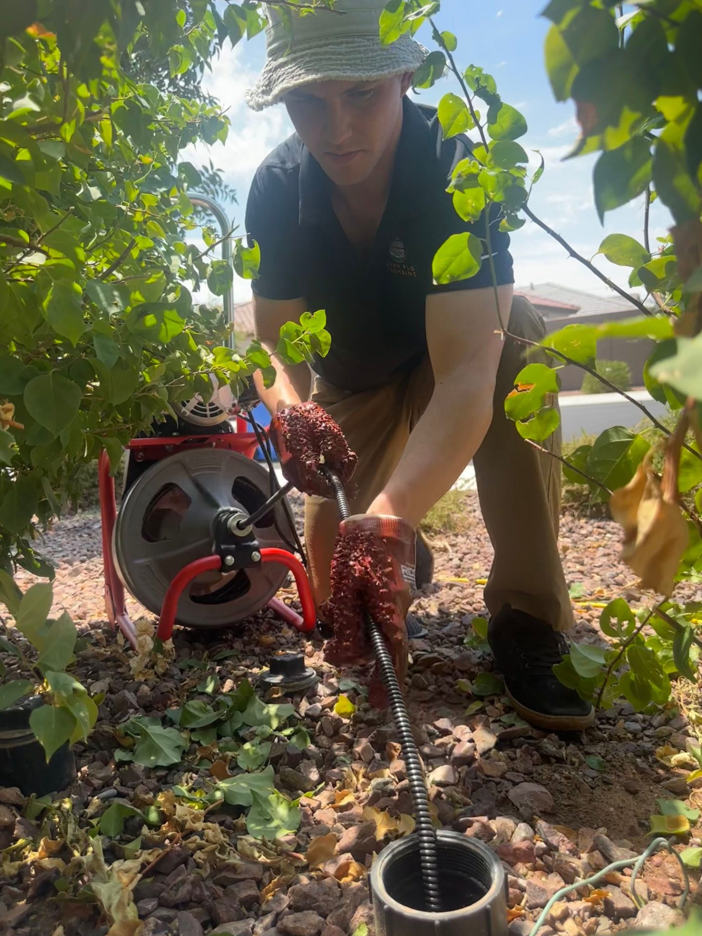 Plumber feeding a drain cable into a sewer cleanout at a Phoenix home